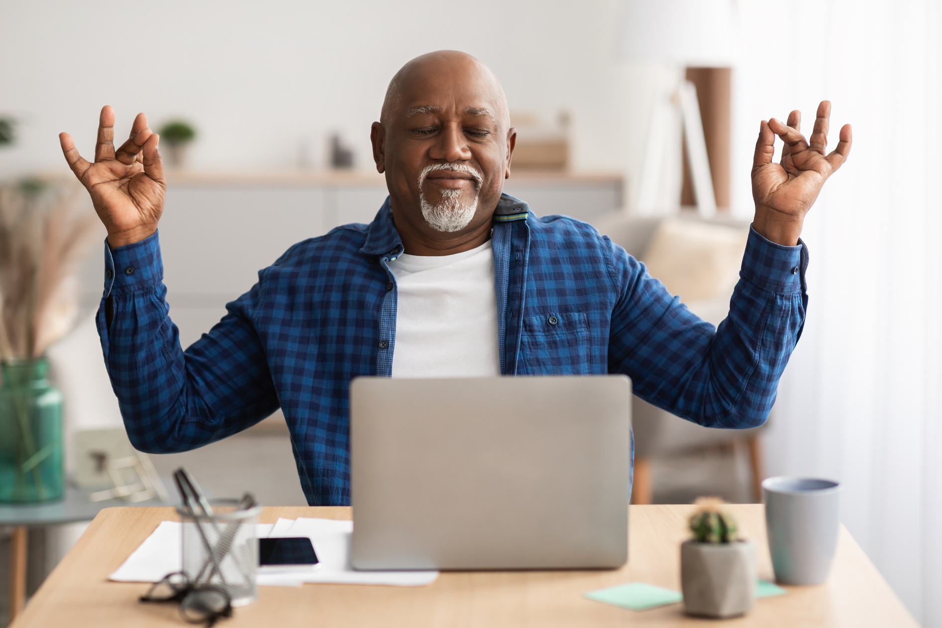 Elderly Man Meditating in Front of a Laptop 
